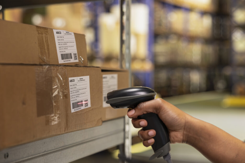 Close up of black woman worker scanning packages in a large storehouse, registering airway bills shipment details within industrial depot records. Using scanner for order fulfillment.